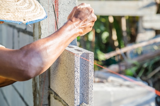 Mury robotnicze budują ściany z bloczków cementowych i zaprawy, układając je warstwami.