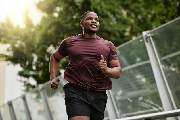 Murzyn fitness i bieganie w parku do zdrowego treningu lub ćwiczeń cardio na łonie natury na świeżym powietrzu Szczęśliwy afroamerykański biegacz biegający lub ćwiczący dla zdrowia i dobrego samopoczucia