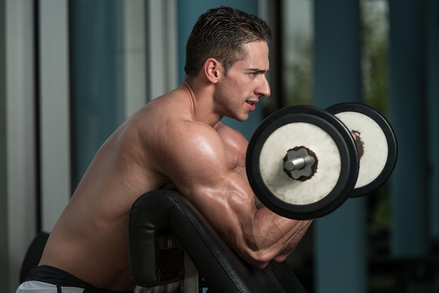 Muskularni mężczyźni wykonujący ciężkie ćwiczenia na biceps