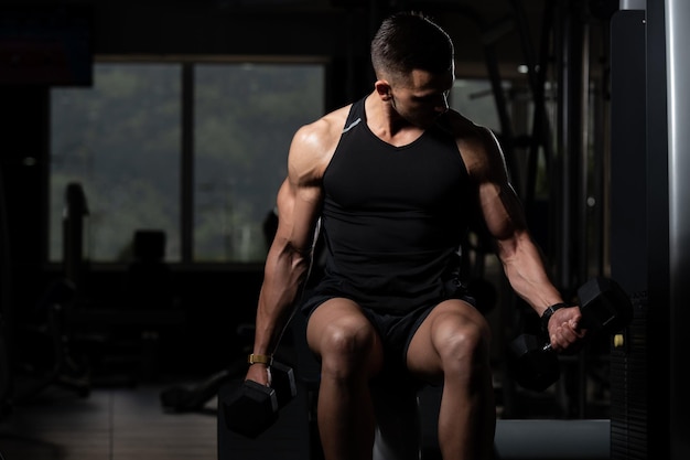 Muskularny mężczyzna ćwiczący biceps z hantlami