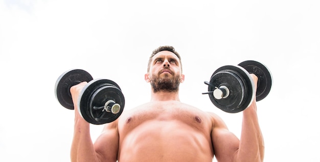 Muskularny mężczyzna ćwiczący z hantlami Sportowiec z silnym torsem Sprzęt sportowy Fitness i kulturystyka Sport Sportowy styl życia Sukces to wybór Zwycięstwo to nawyk Siłownia z hantlami