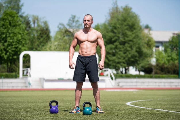 Muskularny mężczyzna ćwiczący z Kettlebell na świeżym powietrzu