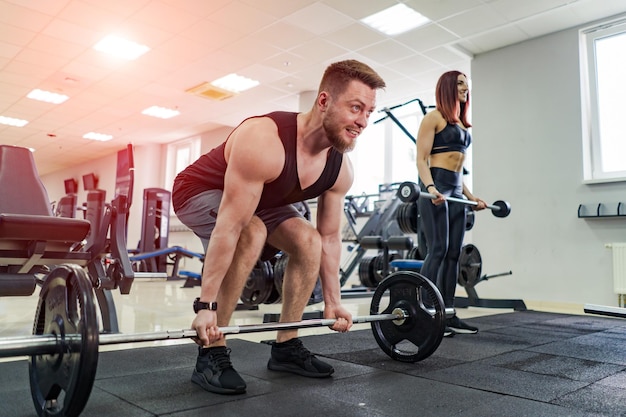 Muskularny Mężczyzna I Młoda Kobieta Podnoszenie Ciężarów Na Siłowni Para Fitness Robi Trening Crossfit Szczęśliwie Na Jasnym Tle Nowoczesny