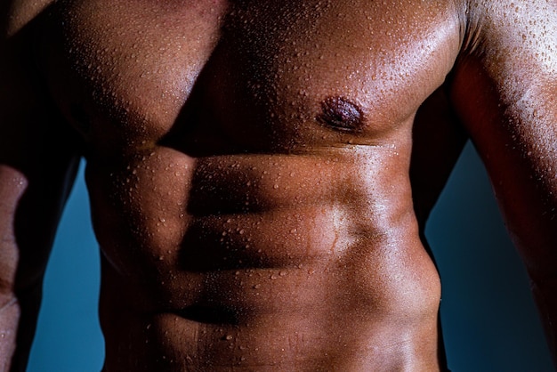 Muskularny mężczyzna model na ciemnym tle muskularny wesoły seksowny z sześciopakiem abs w studio