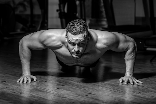 Muskularny mężczyzna robi pompki na jednej ręce na tle siłowni Sport Muskularny i silny facet ćwiczy Muskularny mężczyzna robi pompki Szczupły mężczyzna robi pompki na siłowni Mężczyzna robi pompki