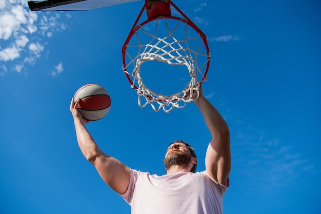 Muskularny mężczyzna rzuca piłkę do koszykówki przez koszyk męski koszykówka