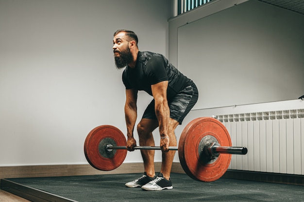 Muskularny Mężczyzna W Czarnej Odzieży Sportowej Podnoszenia Sztangi Na Siłowni