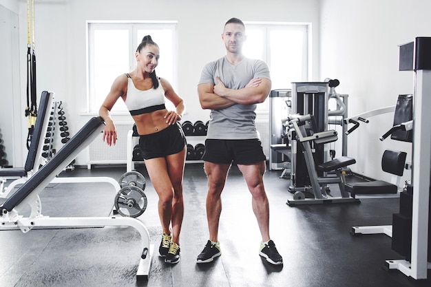 Muskularny przystojny mężczyzna i seksowna brunetka z ciałami fitness pozowanie w koncepcji siłowni programu żywienia sportowego i treningu