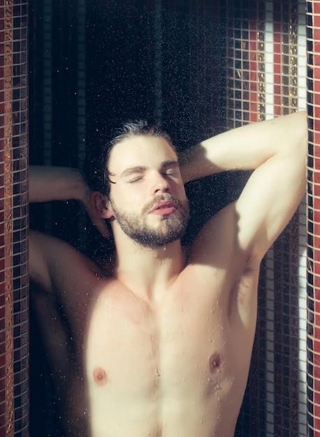 Muskularny przystojny mokry mężczyzna pod prysznicem pod wodą