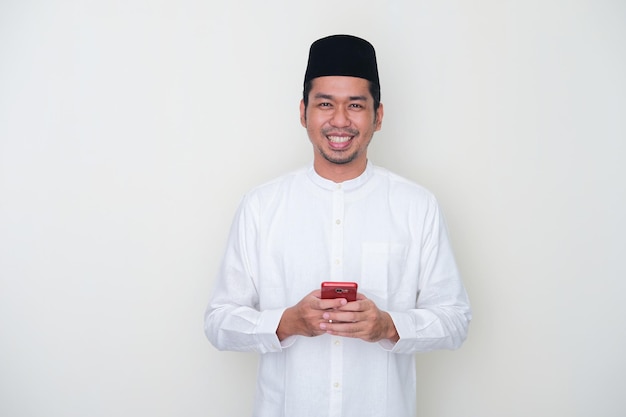 Muzułmanin uśmiecha się do kamery trzymając telefon komórkowy