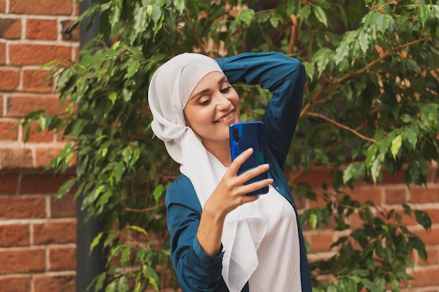 Muzułmanka robi selfie szczęśliwa piękna dziewczyna z szalikiem robi sobie zdjęcie za pomocą smartfona
