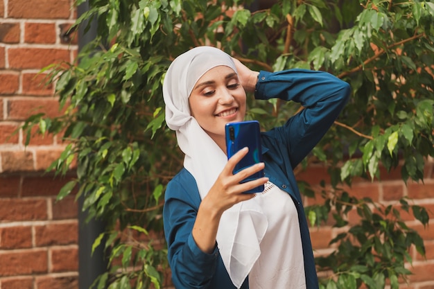 Muzułmanka robi selfie szczęśliwa piękna dziewczyna z szalikiem robi sobie zdjęcie za pomocą smartfona