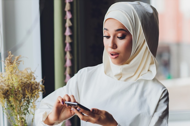 Muzułmanka rozmawia przez telefon komórkowy w kawiarni
