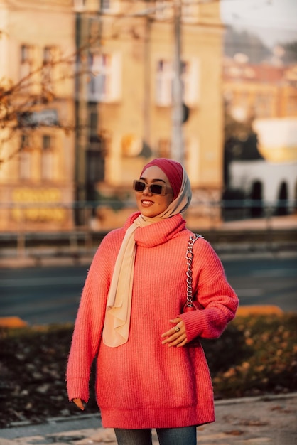 Muzułmanka w hidżabie spaceruje po ulicach miasta w nowoczesnym stroju połączonym z okularami przeciwsłonecznymi Selektywne skupienie