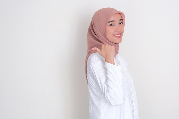 Muzułmańska Azjatka uśmiecha się z jedną ręką wskazującą na tyłek