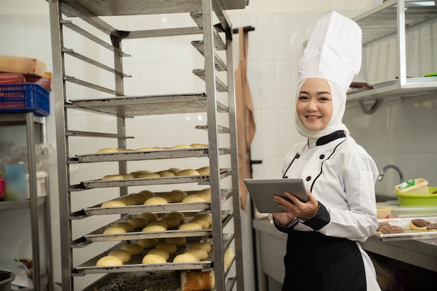 Muzułmańska Baker pracująca w kuchni i trzymając tablet pc