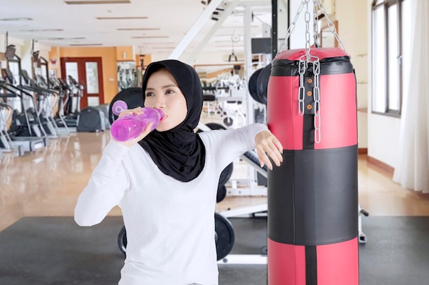 Muzułmańska kobieta pijąca wodę w siłowni