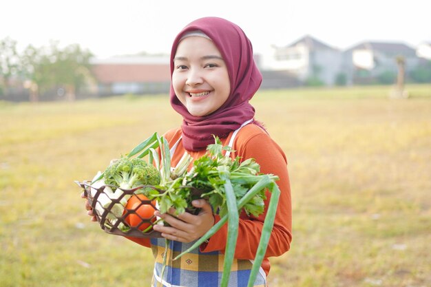 Muzułmańska kobieta w fartuchu trzymająca kosz pełen warzyw