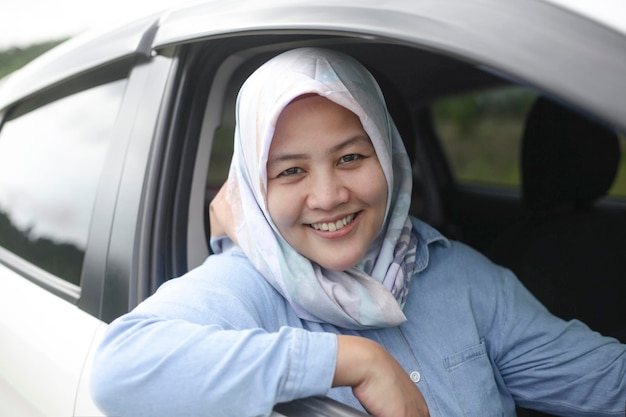 Muzułmańska kobieta z Azji uśmiecha się podczas jazdy samochodem podczas wakacji.