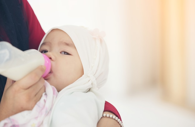 Muzułmańska matka karmi swoje dziecko butelką mleka.