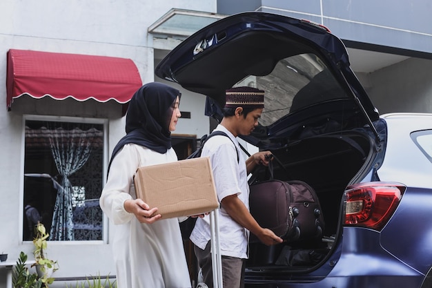 Muzułmańska para przenosi walizkę i karton do bagażnika samochodu.
