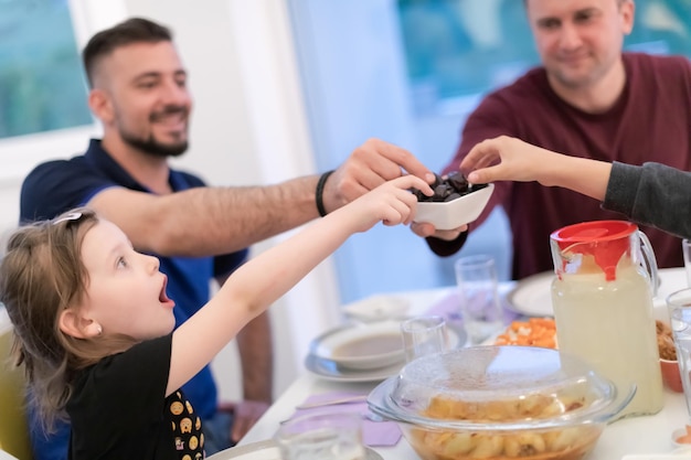 Muzułmańska rodzina Eid Mubarak je kolację iftar, jedząc daktyle, aby przerwać ucztę. Jedzenie tradycyjnych potraw podczas miesiąca biesiadowania Ramadanu w domu. Islamskie jedzenie i picie halal we współczesnym zachodnim islamie