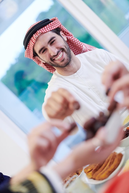 Muzułmańska rodzina Eid Mubarak je kolację iftar, jedząc daktyle, aby przerwać ucztę. Jedzenie tradycyjnych potraw podczas miesiąca biesiadowania Ramadanu w domu. Islamskie jedzenie i picie halal we współczesnym zachodnim islamie