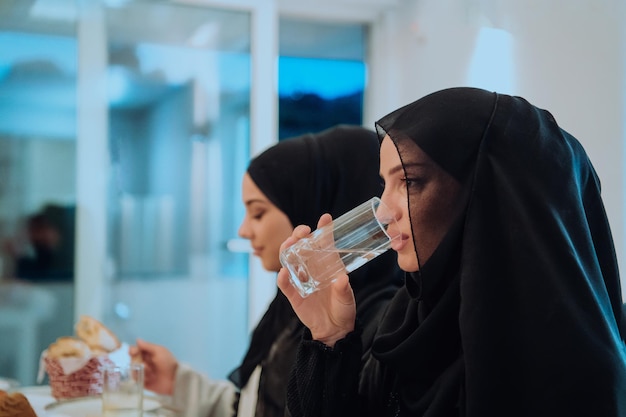 Muzułmańska rodzina Eid Mubarak je kolację iftar, pijąc wodę, aby przerwać ucztę. Jedzenie tradycyjnych potraw podczas miesiąca biesiadowania Ramadanu w domu. Islamskie jedzenie i picie halal na współczesnej zachodniej wyspie