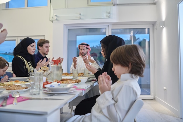 Zdjęcie muzułmańska rodzina robiąca iftar dua, aby przerwać post podczas ramadanu. arabowie trzymają ręce w geście za modlitwę i dziękczynienie allahowi przed tradycyjnym obiadem