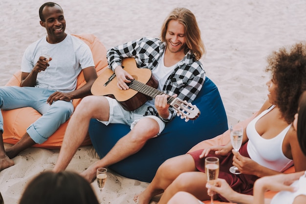 Muzyk grający na gitarze na plaży dla przyjaciół