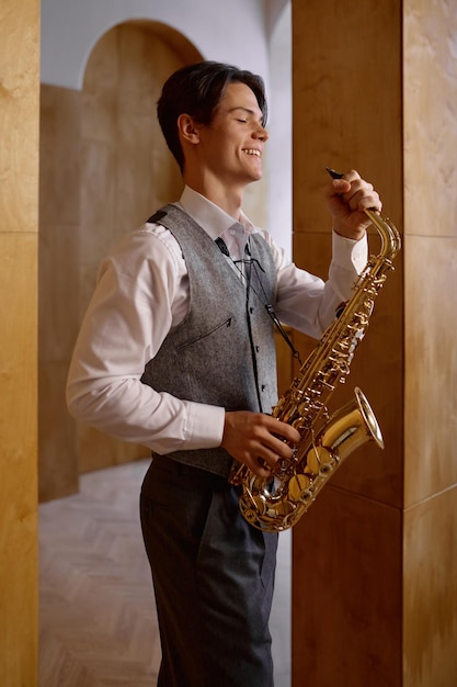 Muzyk jazzowy grający na saksofonie i oparty o ścianę studia artystycznego. Ćwiczenie przed występem
