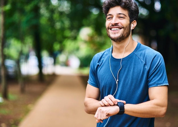 Muzyka fitness i mężczyzna z zegarkiem na postępy w czasie i wyniki serca w parku Pomyśl o uśmiechu i sportowiec słuchający podcastu lub dźwięku podczas sprawdzania powiadomienia na urządzeniu