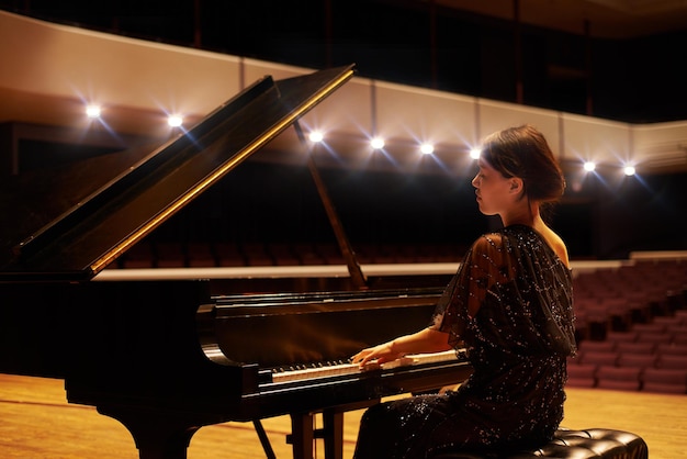 Muzyka to jej sztuka Ujęcie młodej kobiety grającej na pianinie podczas koncertu muzycznego