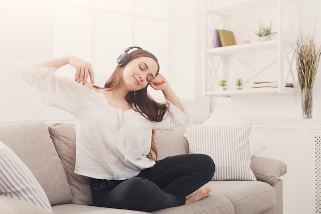 Muzyka ze smartfona. Szczęśliwa kobieta w słuchawkach słuchająca playlisty w domu, z zamkniętymi oczami, kopiująca przestrzeń