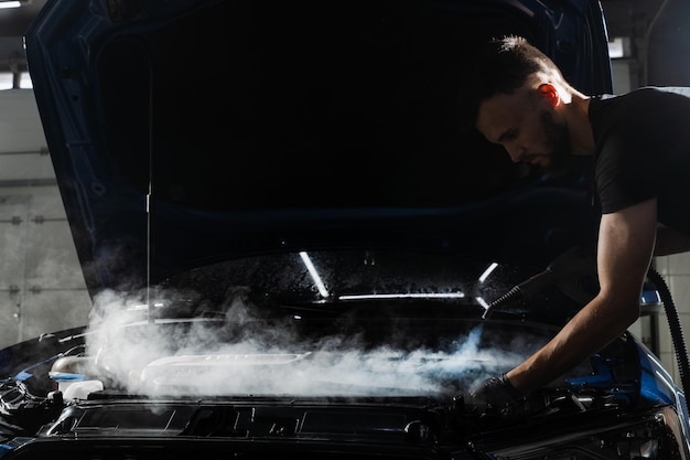 Mycie parowe silnika samochodu w serwisie detailingowym Proces czyszczenia parą silnika samochodu z kurzu i brudu