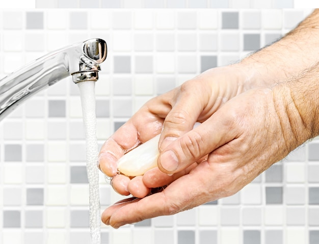 Mycie rąk pod bieżącą wodą z bliska na tle wnętrza łazienki.