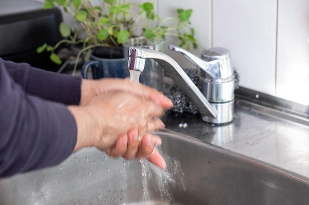 Mycie rąk wodą pod srebrnym kranem w zlewie