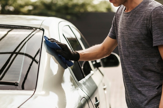 Zdjęcie myjnia samoobsługowa młody człowiek wyciera samochód po umyciu