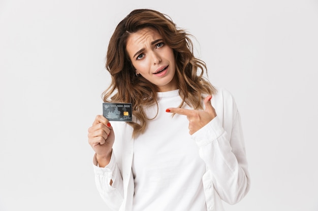 Mylić młoda kobieta pokazuje plastikową kartę kredytową na białym tle