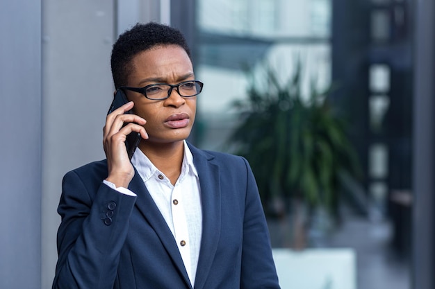 Myśląca kobieta biznesu rozmawiająca przez telefon zdjęcie z bliska portret afroamerykańskiej kobiety w okularach