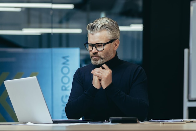 Myślenie człowieka wewnątrz pakietu office w pracy dojrzałe biznesmen dorosłych spojrzenie na ekran laptopa szary haired