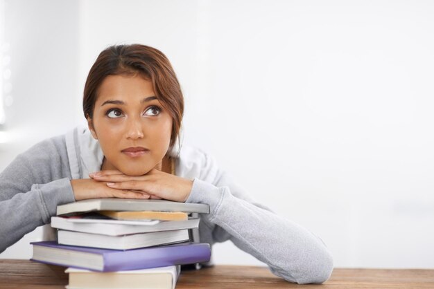 Myślenie o rozwiązaniu problemu Zbliżenie atrakcyjnej studentki, która opiera się o swoje książki i wygląda na zamyśloną