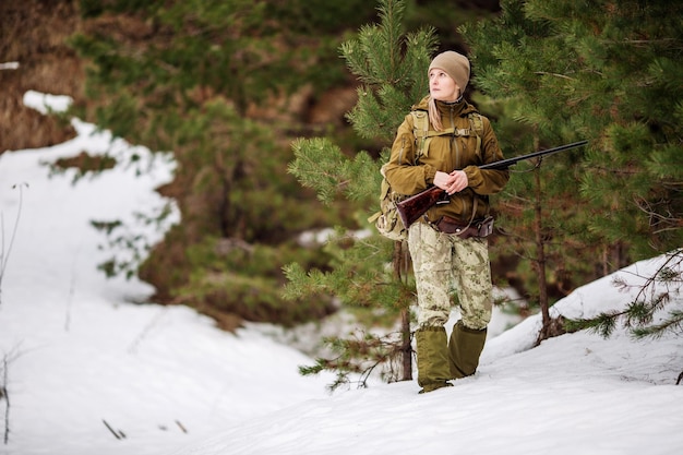 Myśliwy w kamuflażu gotowy do polowania, trzymając pistolet i spacerując po lesie