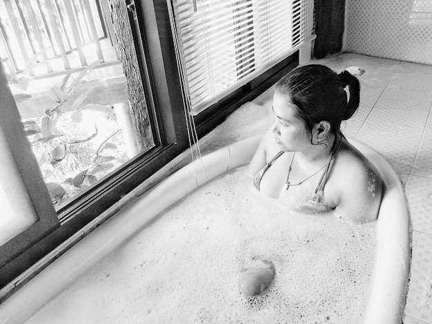 Zdjęcie myślliwa młoda kobieta w wannie w domu
