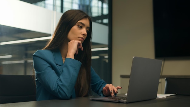 Myślna wahająca się wątpliwa indyjska kobieta pracuje na laptopie w biurze myśląca niepewna zdezorientowana arabska dziewczyna.