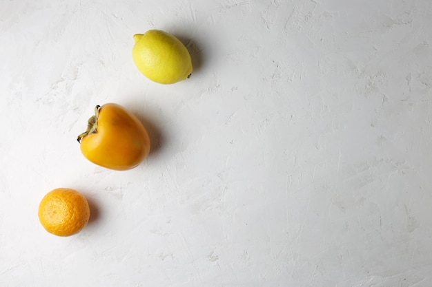 Na białym tle są cytryna, mandarynka, persimmon. Zdrowa żywność, miejsce na kopię.