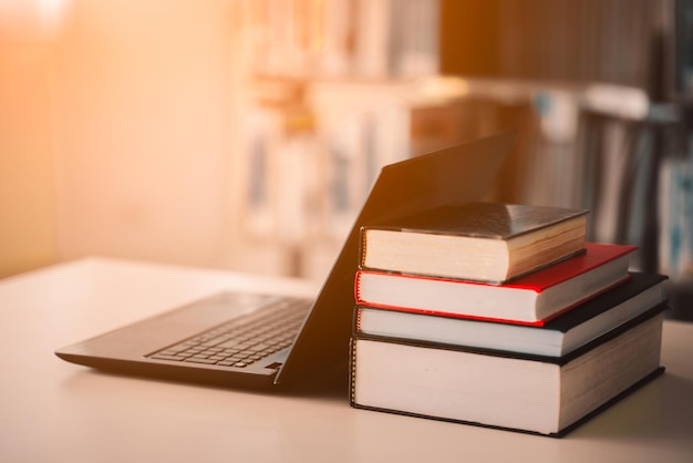 Na biurku bibliotecznym ustawione są półki na książki i laptopy. Zajęcia e-learningowe i technologia cyfrowa e-booków