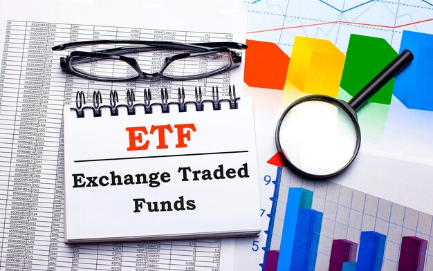 Na Biurku Znajdują Się Okulary, Lupa, Kolorowe Tablice I Biały Notes Z Napisem Etf Exchange Traded Funds. Pomysł Na Biznes. Widok Z Góry