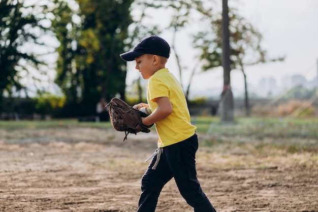 Na boisko biegnie młody baseballista w rękawiczce baseballowej