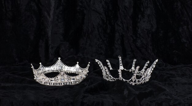 Zdjęcie na czarnym tle znajdują się dwie srebrne korony, z których jedna to korona.